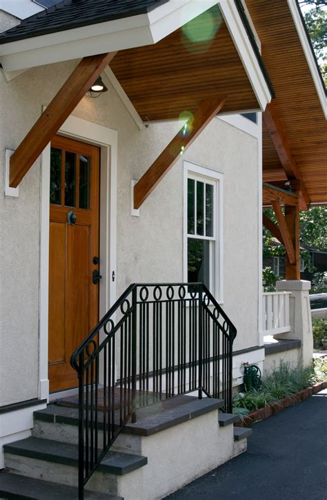 A White House With Black Railing And Wooden Door