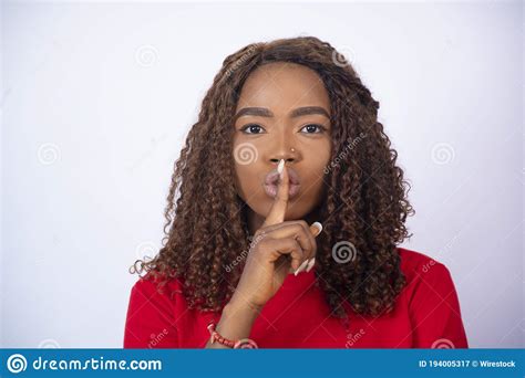 Young African Lady With Her Finger Over Her Mouth Gesturing For