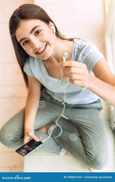 Top View Of Pleasant Teenage Girl Offering One Earphone Stock Image