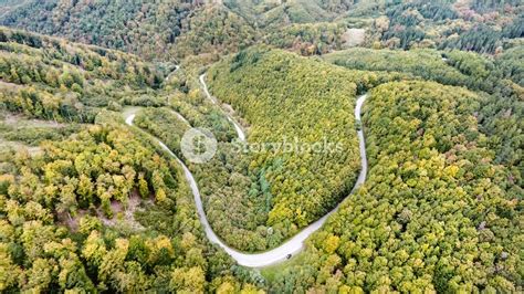 Aerial View Of Curvy Road In The Middle Of Green Forest Low Hills