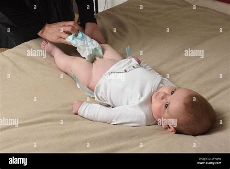 Changing The Diaper On The Baby Who Is Lying In Bed Stock Photo Alamy