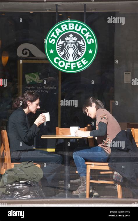 Two Woman Sat At The Window Inside A Branch Of Starbucks Coffee On The Strand Central London