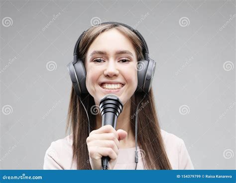 Muchacha Expresiva Que Canta Con Un Micrfono Y Los Auriculares Imagen