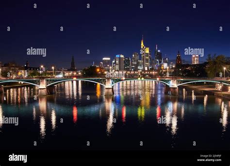 Frankfurt Skyline And Illuminated Ignatz Bubis Bridge Reflecting In The