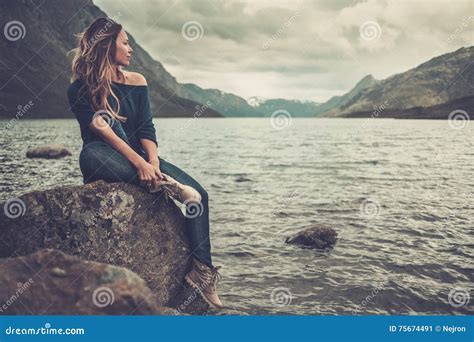 Beautiful Woman Posing On The Shore Of A Wild Lake With Mountains On
