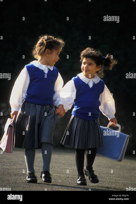 Two Little Girls In School Uniform Carrying Schoolbags Walking To