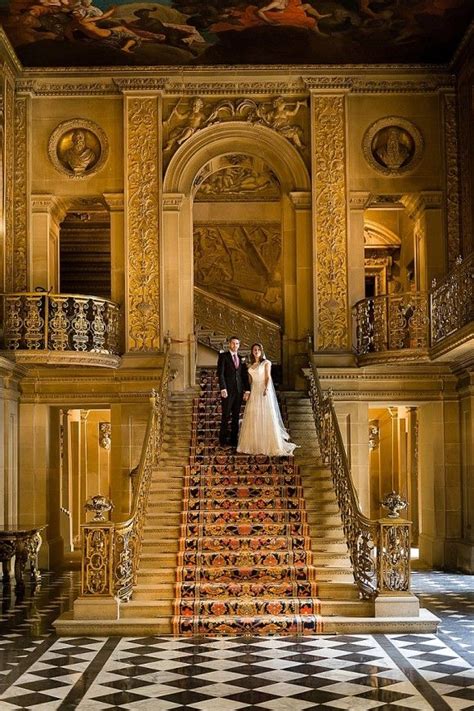 A Bride And Groom Are Standing On The Stairs In An Ornately Decorated