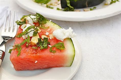 A Slice Of Watermelon With Feta Cheese And Mint On It Next To A Fork