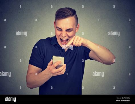 Portrait Angry Young Man Screaming On Mobile Phone Isolated On Gray