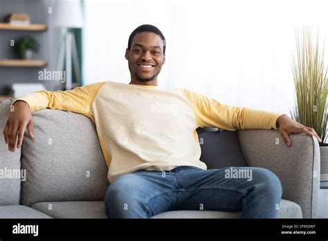 Happy Black Man Sitting On Sofa At Home Stock Photo Alamy