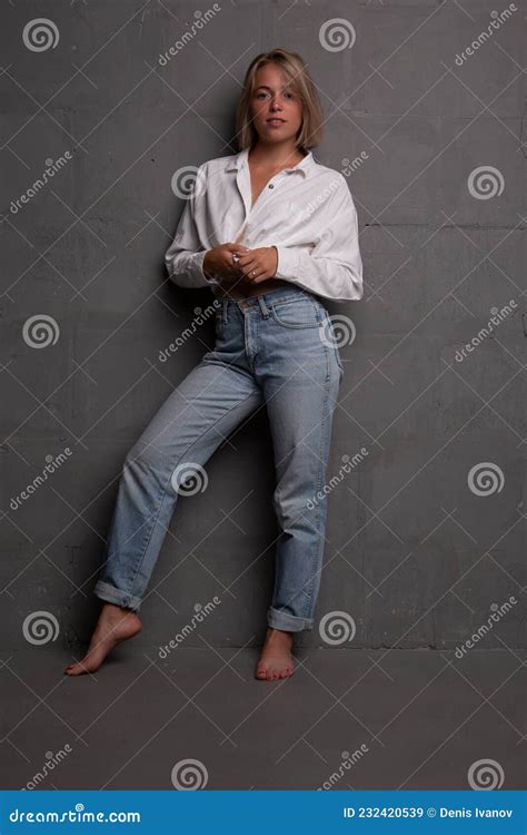 Young Woman With A Beautiful Figure In Jeans And An Unbuttoned Shirt