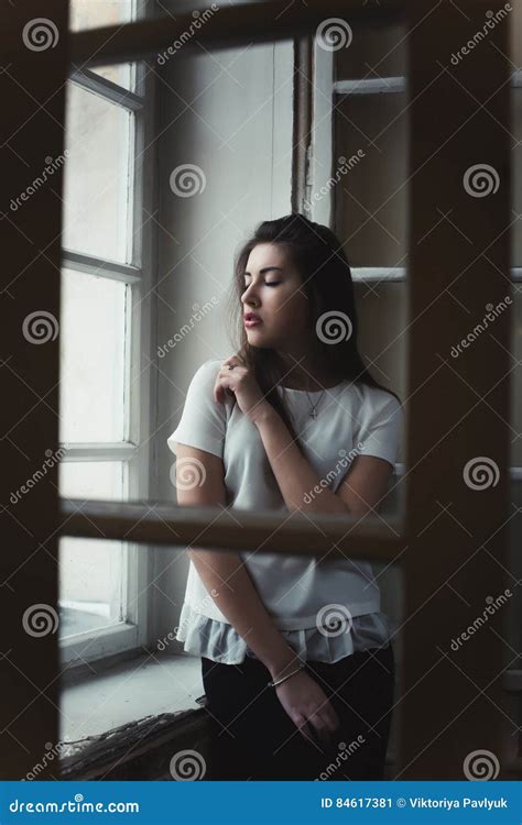 Attractive Young Brunette Woman Standing Behind The Window Stock Image