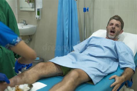 Anonymous Doctor Treating Leg Wound Of Scared And Worried Man In Pain