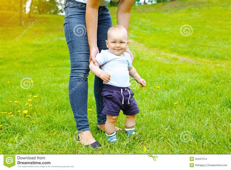 Mother And Baby Walking Together On The Grass In Summer Stock Photo