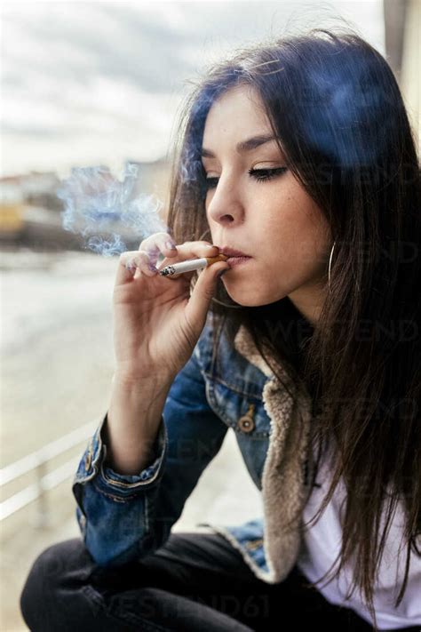 Young Woman Smoking A Cigarette Outdoors Stock Photo