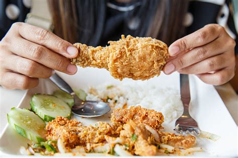 Beautiful chinese american woman eating a fried chicken drumstick and a mug of beer isolated on a mother with baby eating healthy meal. Hand Holding Fried Chicken And Eating In The Restaurant ...