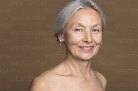 Portrait Of Naked Senior Woman In Front Of Brown Background Stock Photo