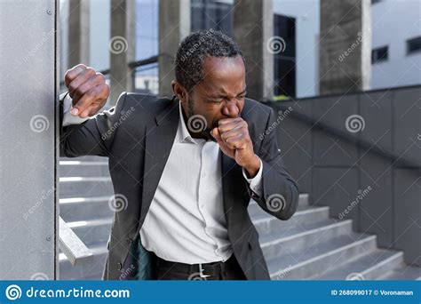 An African American Businessman In Outside Coughing Hard Covering His