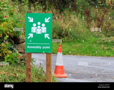 Green And White Assembly Point Sign Fitted To Wooden Post Stock Photo