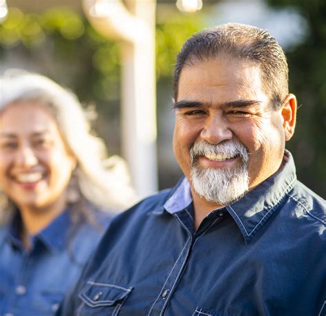 Senior Mexican Man Smiling With Wife In The Background