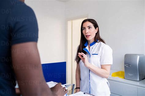 Nurse Speaking With Patient At Hospital Reception Stock Photo