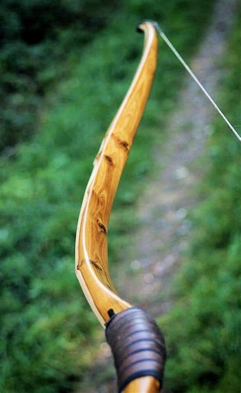 A Bow And Arrow On The Back Of A Wooden Bicycle Handlebars In Front Of