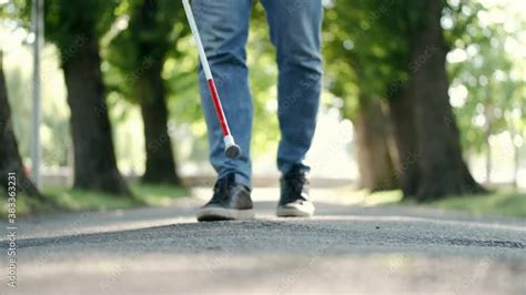 Stockvideon Blind Man Walking In Park Using Long Cane To Scan Way For