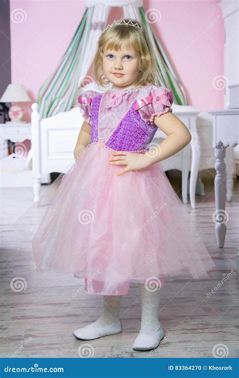 Little Happy Princess Girl In Pink Dress And Crown In Her Royal Room Posing And Smiling Stock