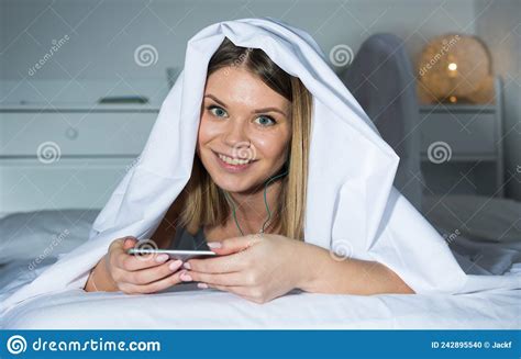 Young Woman Under Blanket On Bed With Mobile Phone Stock Photo Image