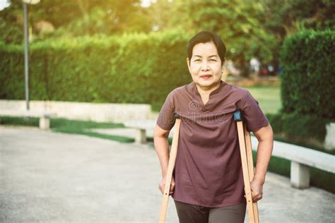 Patient Mature Asian Woman Using Crutches Support Broken Legs For