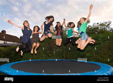 Horizontal Close Up Portrait Of A Group Of Girl Friends Jumping On A Trampoline In A Garden
