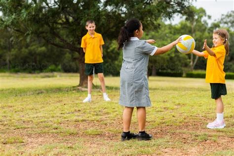 Image Of Happy Healthy School Kids Throwing A Ball To One Another