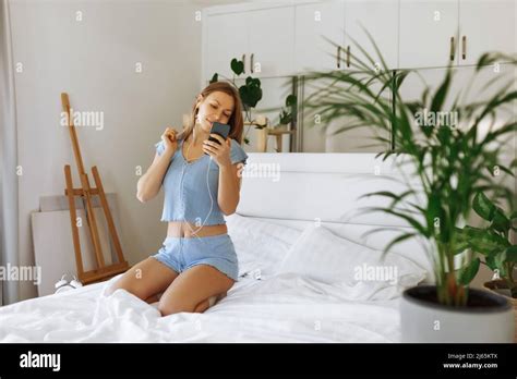 Junge Teenager Mädchen In Pyjama Auf Ihrem Bett Stehen Und überprüfen Smartphone Fröhliches