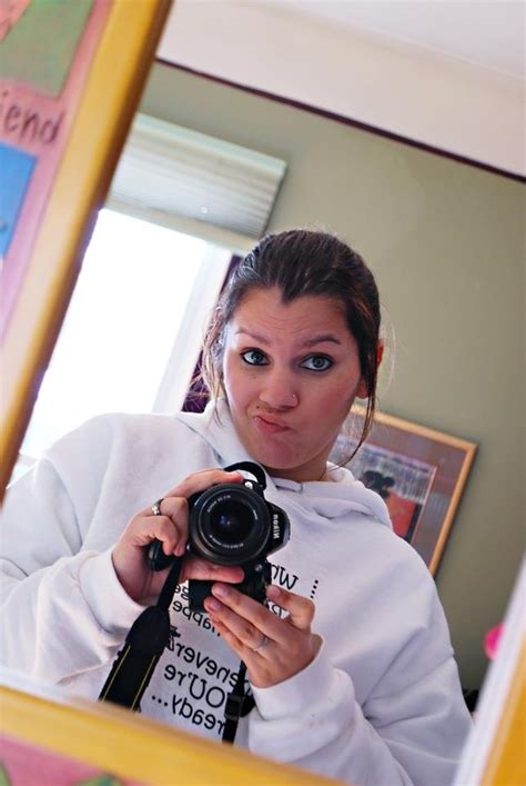 A Woman Taking A Selfie In Front Of A Mirror With A Camera On It