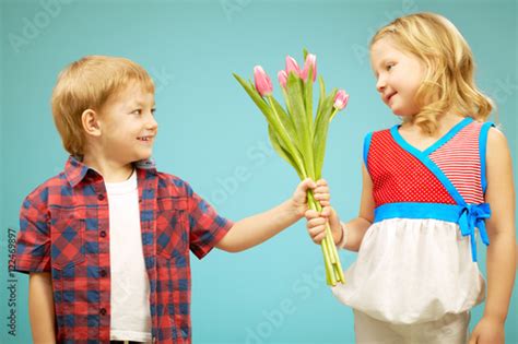 Cute Little Boy Giving Flowers To Pretty Little Girl Stock Photo And