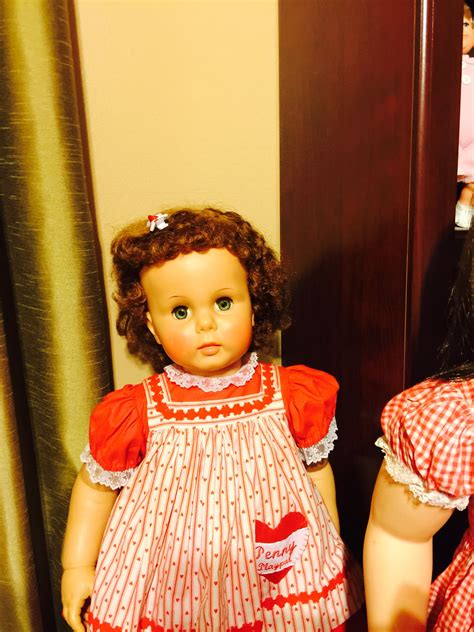 Two Dolls Sitting Next To Each Other In Front Of A Door With Curtains