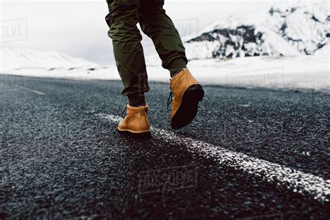 Low Section Of Man Walking On Road During Winter Stock Photo Dissolve