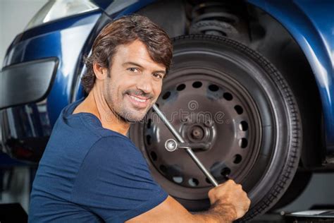 Smiling Mechanic Fixing Car Tire With Rim Wrench Stock Photo Image Of