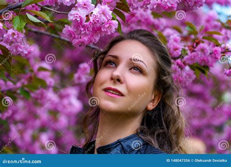 Portrait Of Beautiful Girl In Blooming Pink Flowers Of Sakura In The