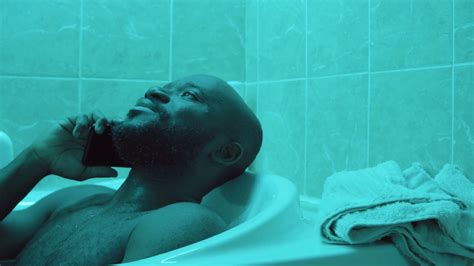 African American Man Resting In Bathtub And Speaking On Mobile Phone
