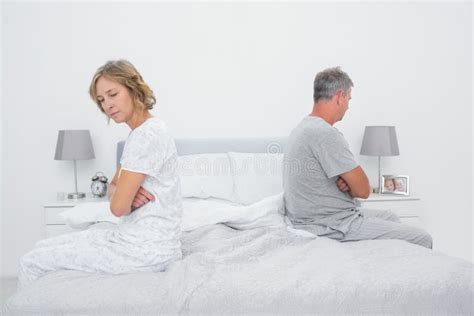 Couple Sitting On Different Sides Of Bed Not Talking After Fight Stock