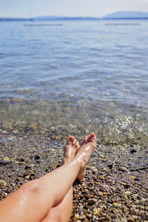 Female Legs A Girl Is Sunbathing On Pebble Beach Of Geneva Lake