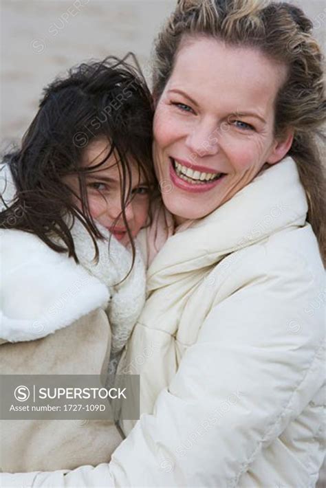 Close Up Of A Mid Adult Woman Hugging Her Daughter On The Beach Superstock