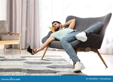 Lazy Man Playing Video Game While Lying On Sofa At Home Stock Photo