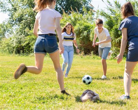 Teenagers Playing Football On Green Grass In Summertime Stock Photo