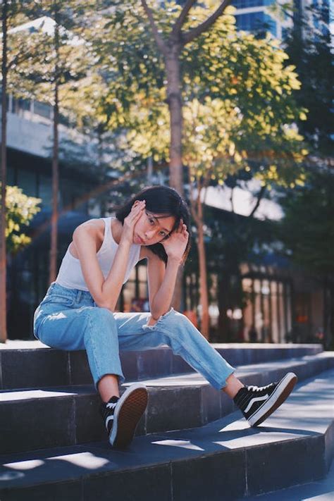 Woman In White Dress Shirt And Blue Denim Jeans Sitting On Wooden Floor