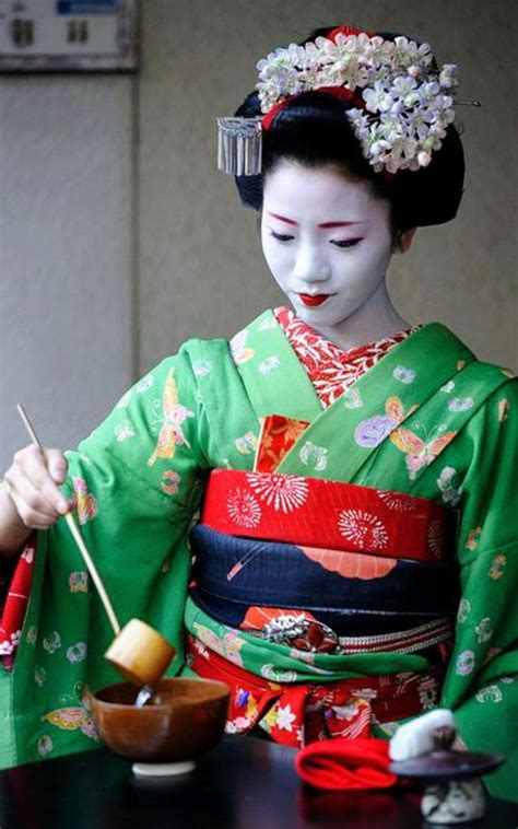 a geisha woman dressed in traditional japanese clothing with chopsticks and bowl of food
