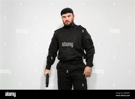 Security Guard Man In Black Uniform With A Baton In His Hands On A