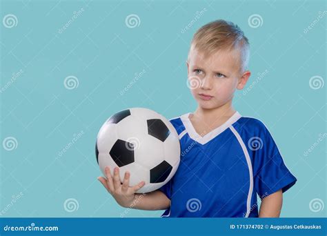 Happy Little Kid In Sportswear Holding A Soccer Ball Isolated On Blue