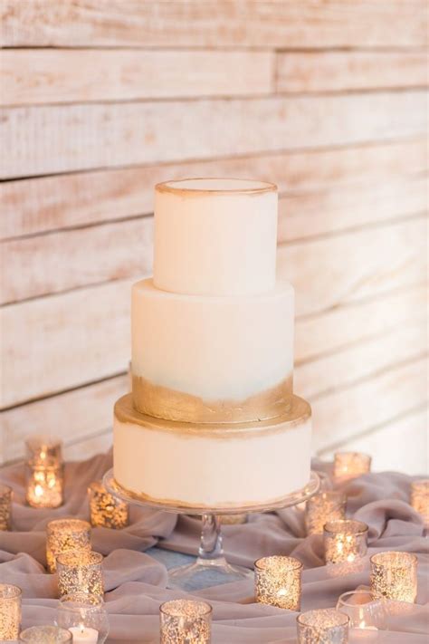 A White Wedding Cake Sitting On Top Of A Table Covered In Candles And Cloths